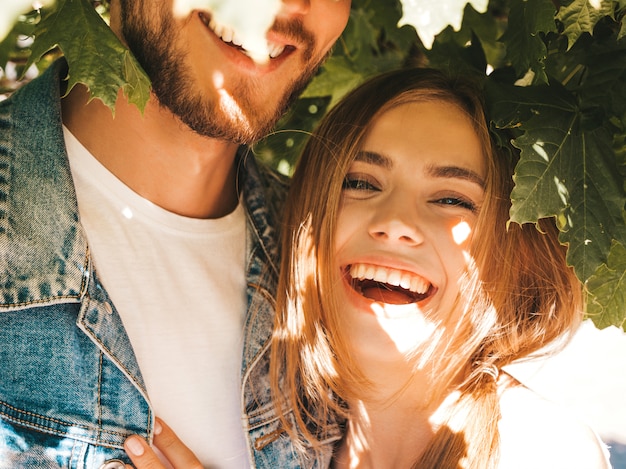 Free photo smiling beautiful girl and her handsome boyfriend posing in the street near tree.