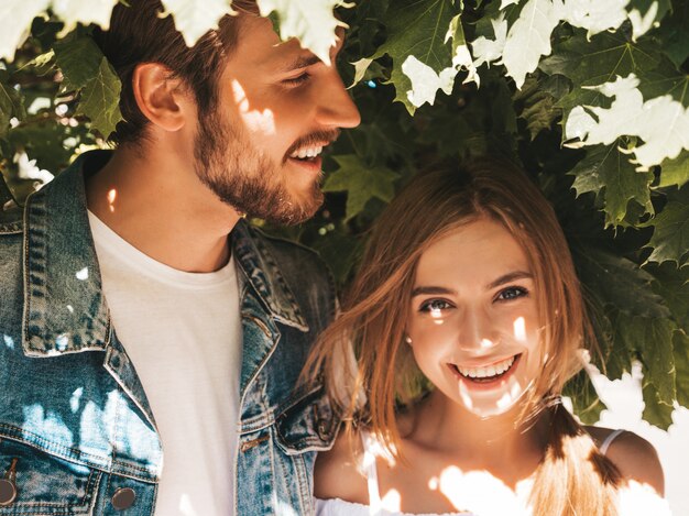 Smiling beautiful girl and her handsome boyfriend posing in the street near tree.