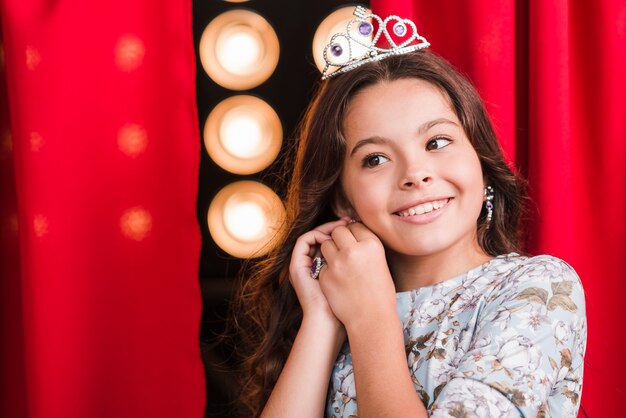 Smiling beautiful girl standing in front of curtain wearing earring