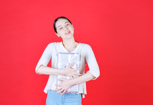 Bella signora sorridente che abbraccia la sua confezione regalo