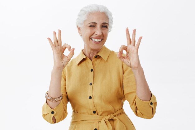 Улыбающаяся красивая старшая женщина показывает нормальный жест, одобряет и любит идею, рекомендует продукт