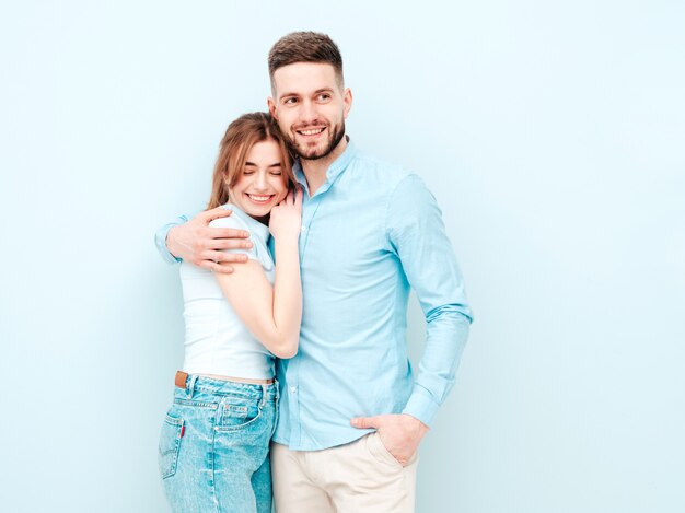 Smiling beautiful woman and her handsome boyfriend. Happy cheerful family having tender moments near light blue wall in studio