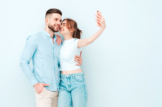 Smiling beautiful woman and her handsome boyfriend. Happy cheerful family having tender moments near light blue wall in studio