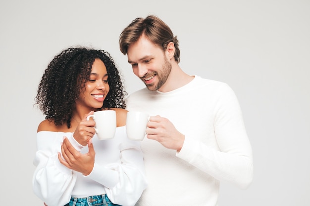 Smiling beautiful woman and her handsome boyfriend. Happy cheerful multiracial family having tender moments on grey