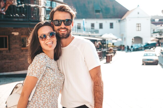 Smiling beautiful woman and her handsome boyfriend Woman in casual summer clothes Happy cheerful family Female having fun Couple posing on the street background in sunglassesHugging each other