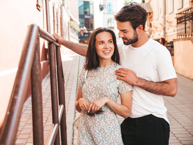 Smiling beautiful woman and her handsome boyfriend Woman in casual summer clothes Happy cheerful family Female having fun Couple posing on the street backgroundHugging each other