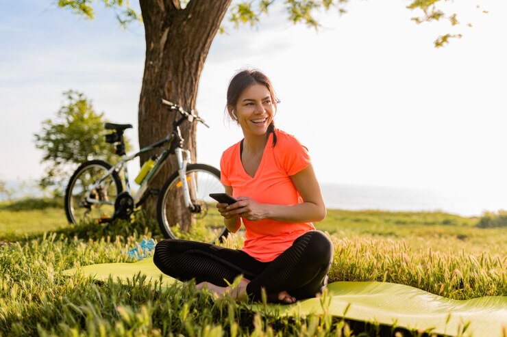 Free Photo smiling beautiful woman holding phone doing sports in morning in park