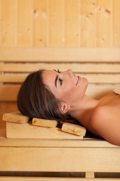 Smiling beautiful woman resting in sauna
