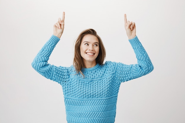 Free photo smiling beautiful woman in sweater pointing fingers up