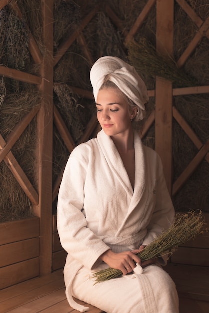 Smiling beautiful young woman sitting on bench at sauna