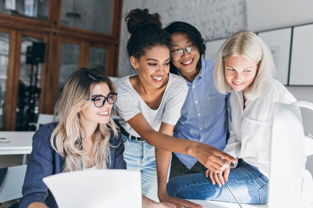 Smiling black girl spending time in office, joking with colleagues