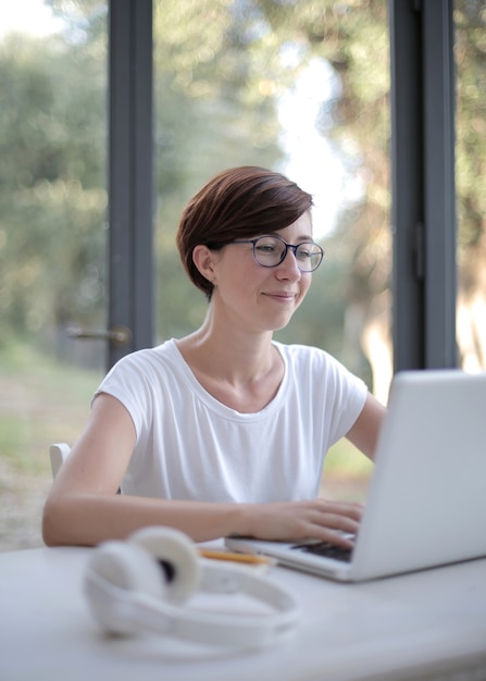 Sorridente signora dai capelli neri che lavora al suo computer portatile in camera