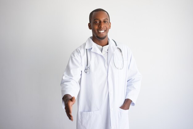 Smiling black male doctor extending arm for handshake. 