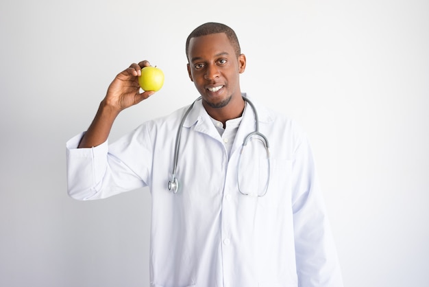 Улыбается черный мужчина-врач показывает и рекомендует apple.
