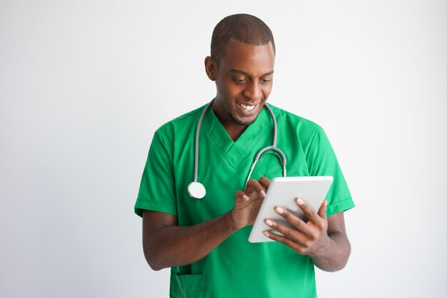 Smiling black male doctor using tablet computer. Technology in medicine concept.