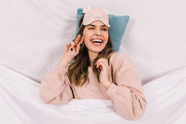 Smiling blissful woman in pajama lying in bed