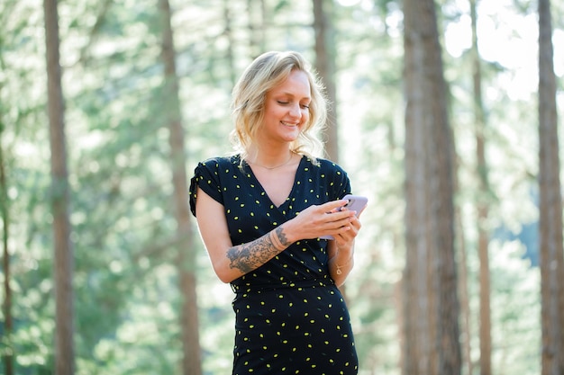 Smiling blogger girl is chatting on mobile on nature background