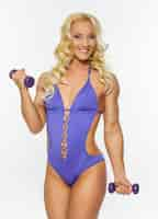 Free photo smiling blond woman in purple swimwear holds small dumbells.