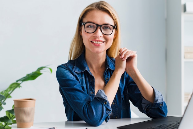 Smiling blonde employee with glasses looking at camera