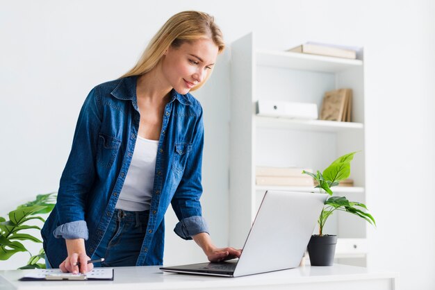 Smiling blonde employee working at laptop