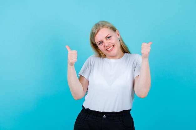 Smiling blonde girl is showing perfect gestures on blue background