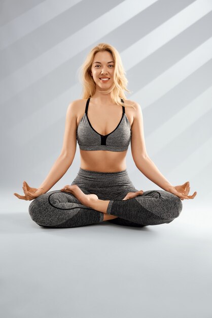 Smiling blonde woman practicing yoga and meditation