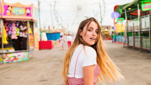 Giovane donna bionda sorridente al parco di divertimenti