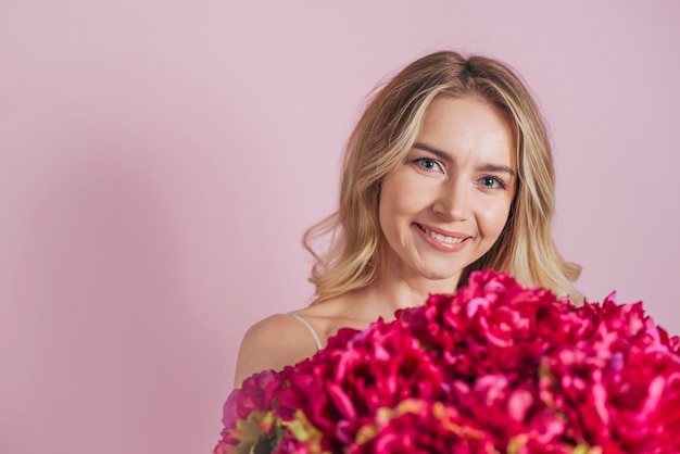 Smiling blonde young woman holding flower bouquet