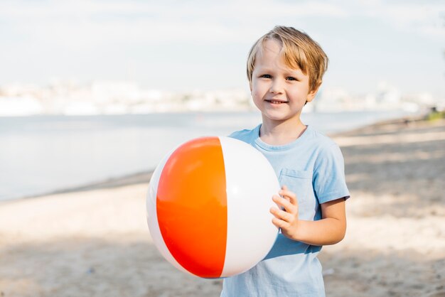 Улыбающийся мальчик, перевозящих пляжный мяч
