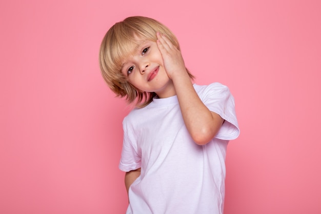Smiling boy cute little adorable in white t-shirt on pink wall