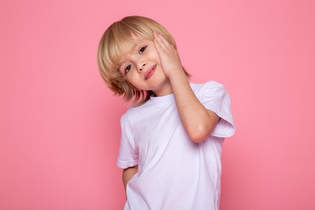 ピンクの壁に白いtシャツで愛らしいかわいい男の子の笑顔