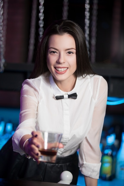 Smiling brunette bartender offering drink