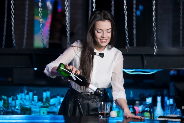 Smiling brunette bartender serving drink