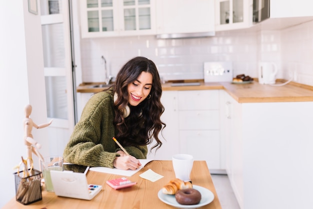 Free photo smiling brunette drawing in kitchen