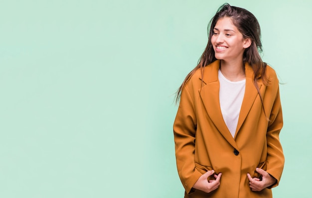 Ragazza castana sorridente che posa con il cappotto