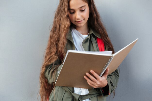 Smiling brunette schoolgirl with long hair dressed in warm clothes