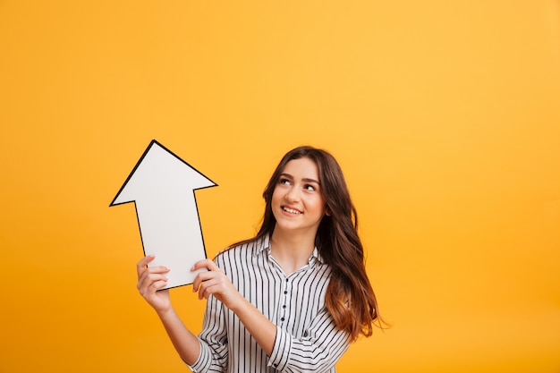 Smiling brunette woman in shirt pointing with paper arrow up