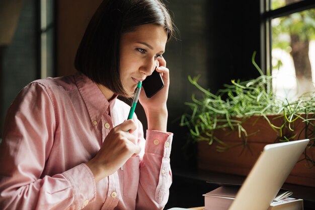 カフェのテーブルに座っている笑顔のブルネットの女性