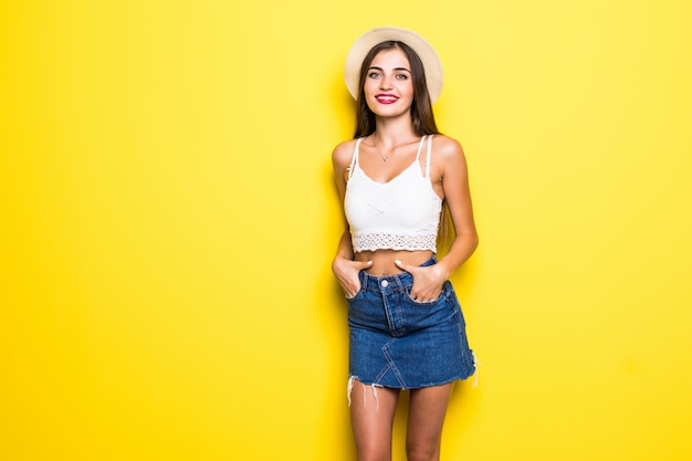 Free photo smiling brunette woman in sweater posing with crossed arms over yellow wall