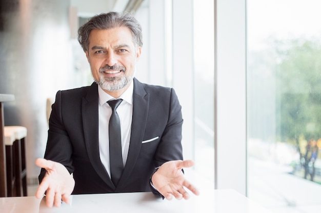 Smiling Business Leader Gesturing at Empty Desk