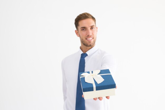 Smiling business man giving gift box with ribbon