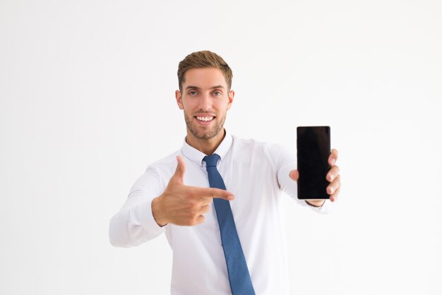 Smiling business man pointing at smartphone