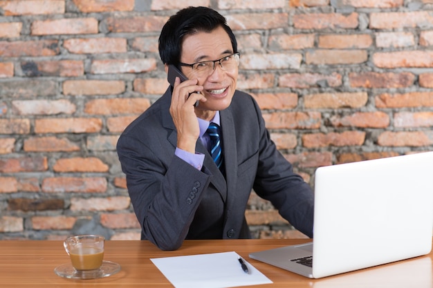 Smiling Business Man Talking on Phone at Desk