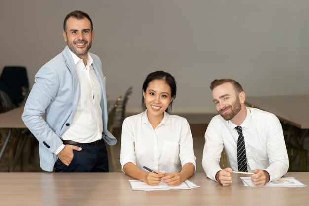 Smiling business people posing at desk in office