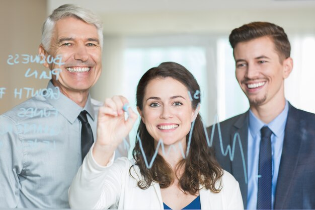 Smiling Business Team Drawing Graph on Glass Screen