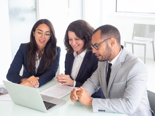 Smiling business team using laptop