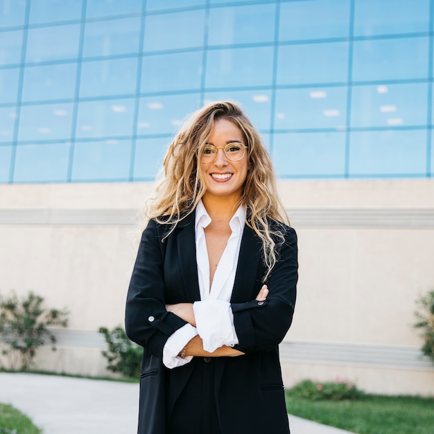 Smiling business woman in front of glass building