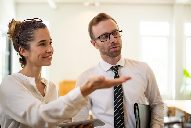 Smiling business woman presenting something to male colleague. 