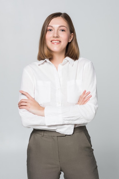 Foto gratuita sorridente donna d'affari con le mani giunte contro il muro bianco. sorriso a trentadue denti, braccia incrociate.