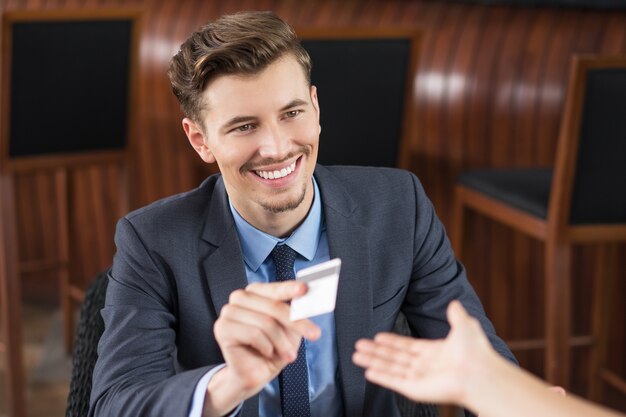 Smiling Businessman Giving Card to Waiter in Cafe